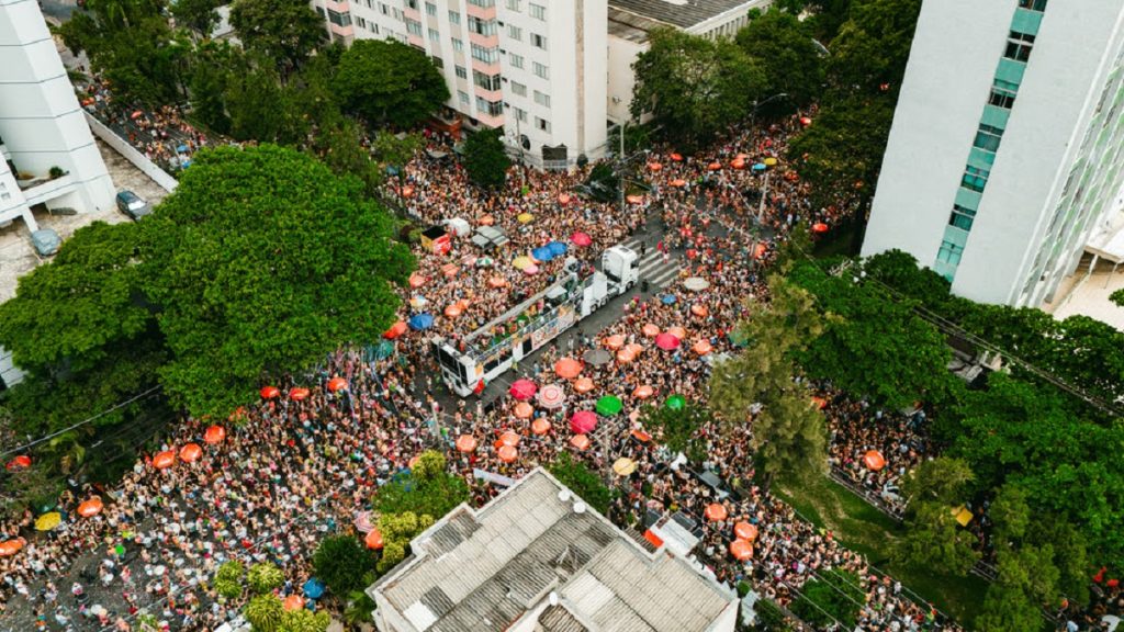 Multidão no bloco de rua Juventude Bronzeada com trio elétrico e guarda-chuvas coloridos em Belo Horizonte