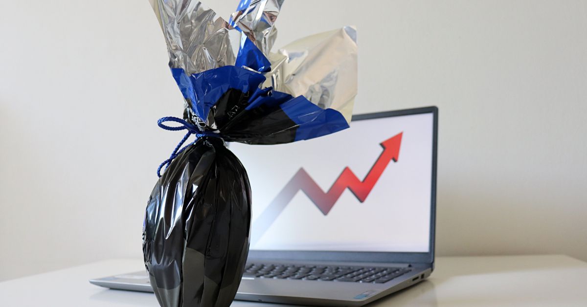 Ovo de Páscoa preto e prata com um laptop exibindo um gráfico de crescimento financeiro.