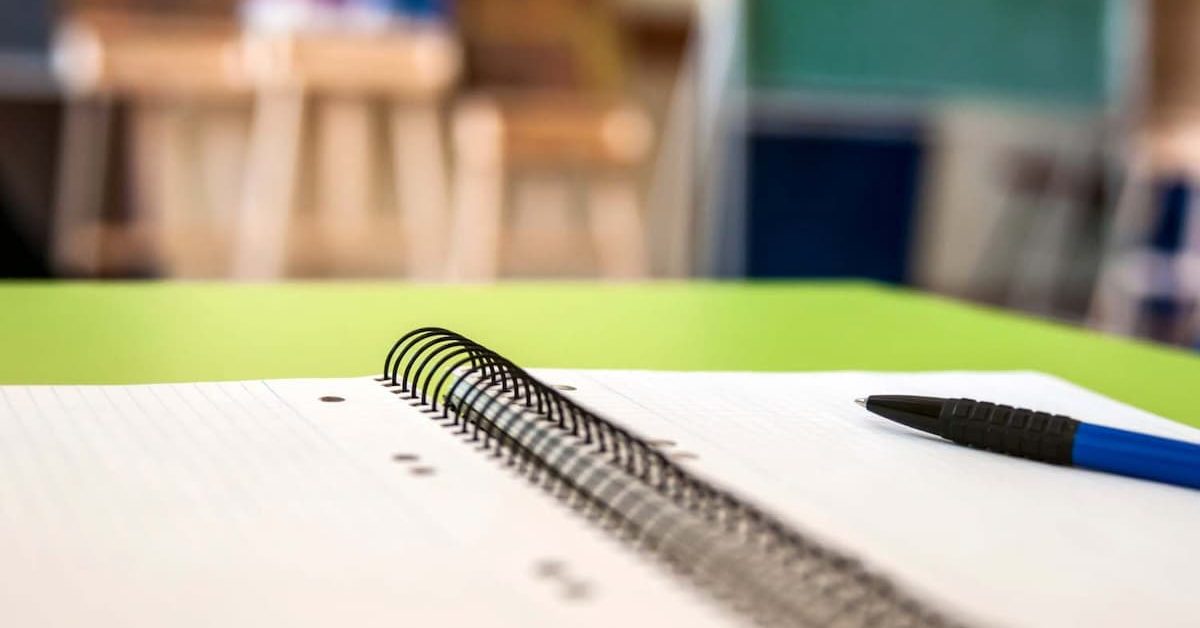 Caderno e uma caneta, em uma sala de aula