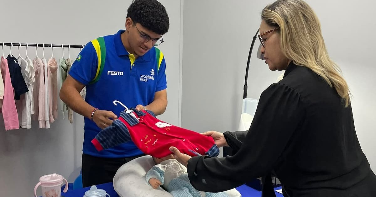 Atendente e cliente analisando um macacão de bebê vermelho