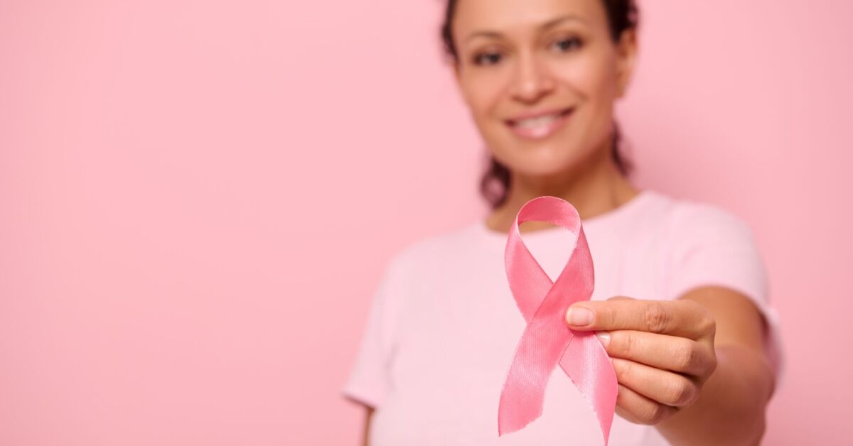 Mulher segurando um laço rosa em apoio à conscientização do câncer de mama