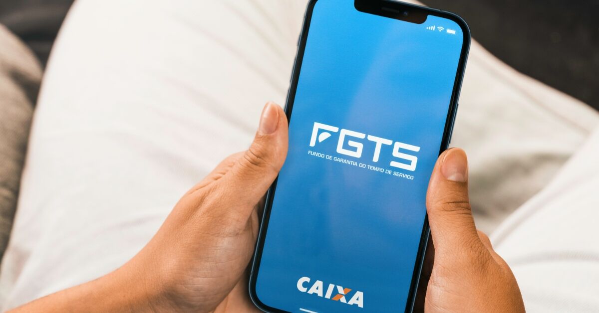 mão feminina segurando um celular ligado na aplicativo do FGTS